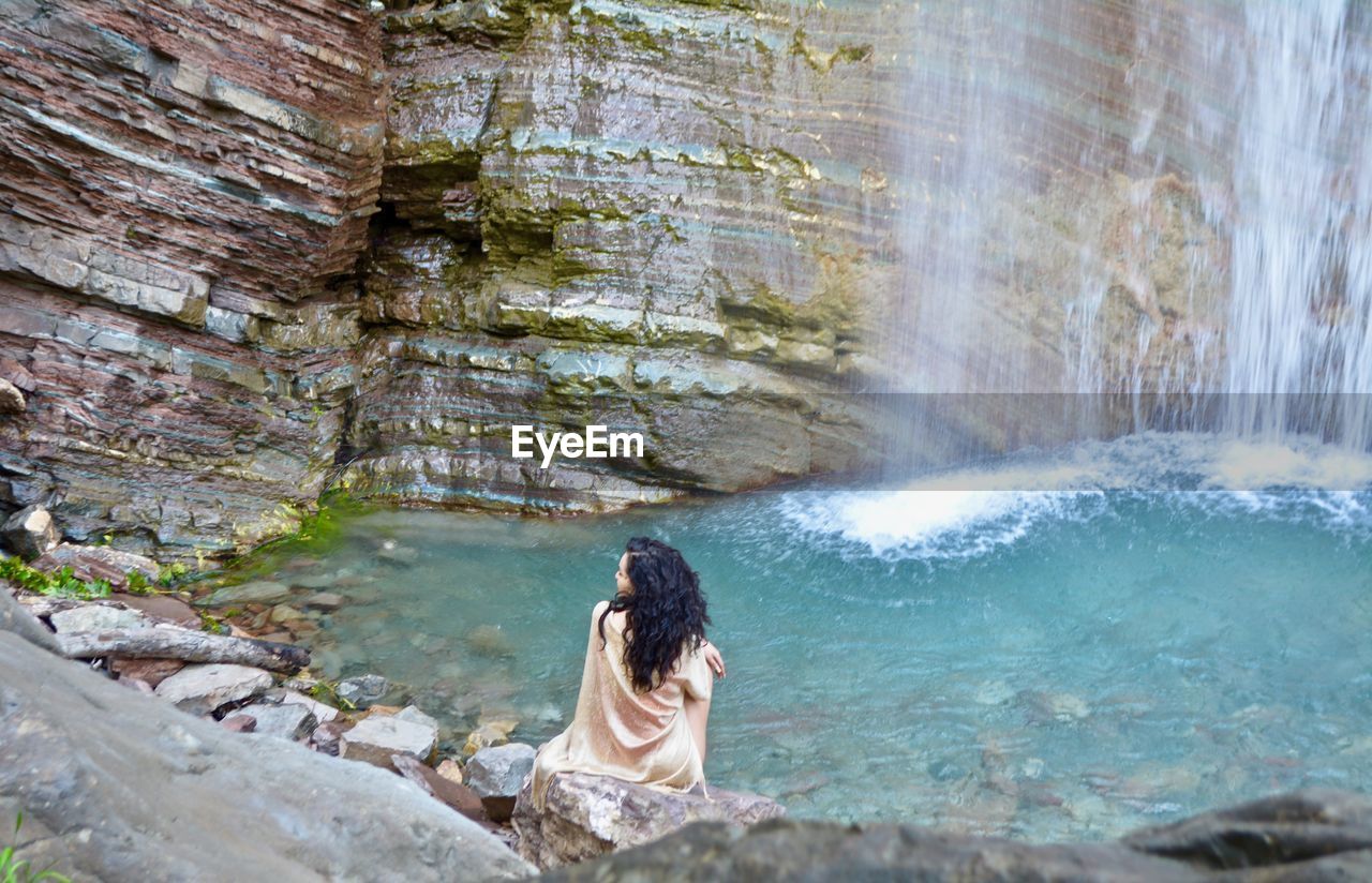 Rear view of woman looking at waterfall