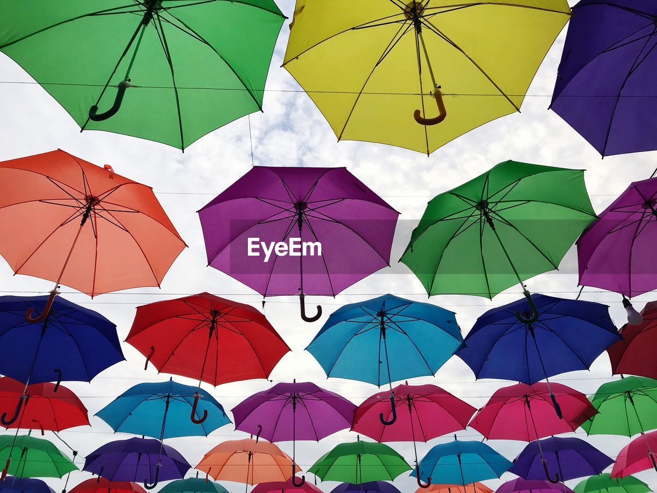 Low angle view of colorful umbrellas hanging against sky