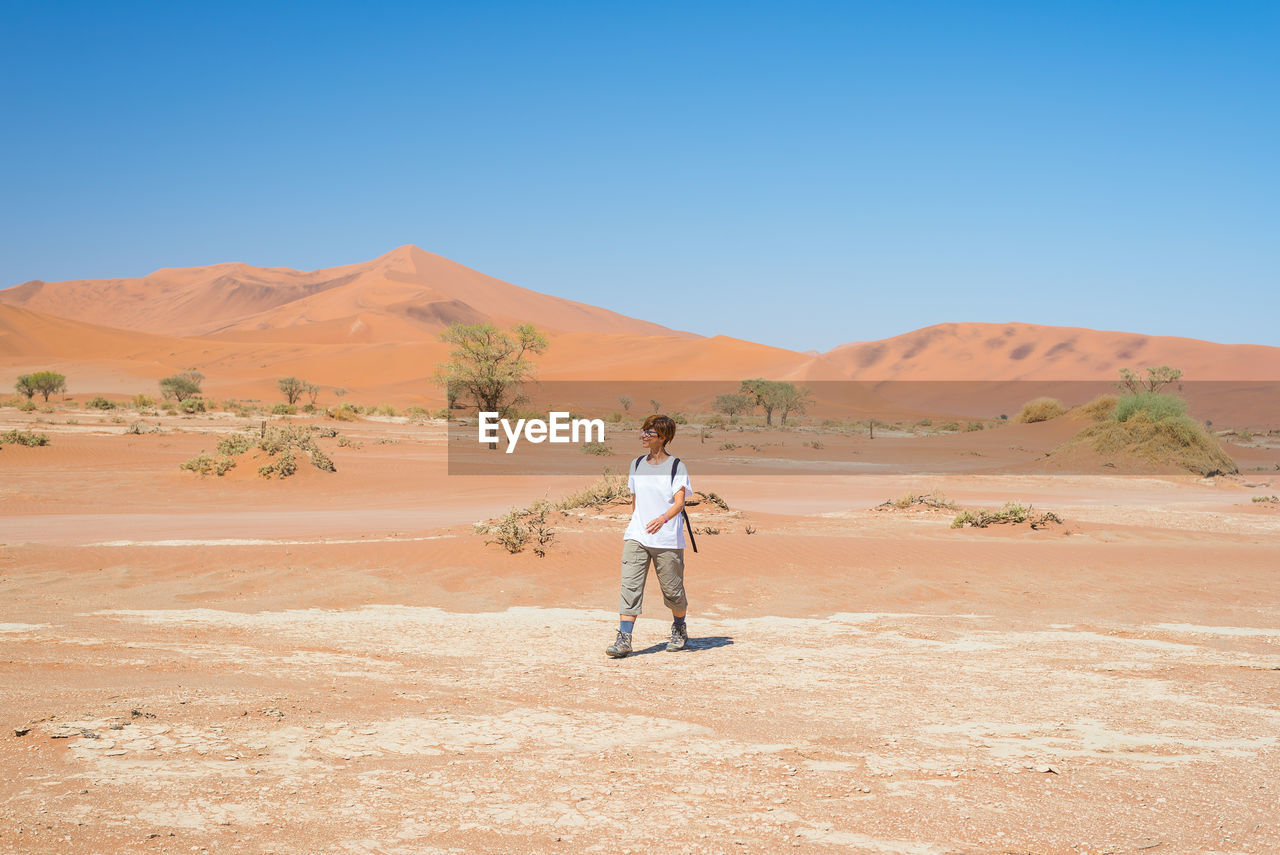 Hiker walking in namib desert against clear sky during sunny day