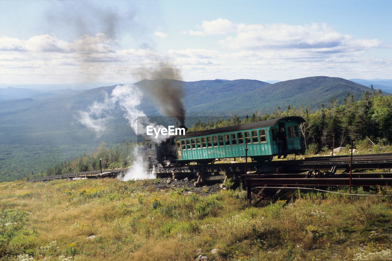 Steam train of mount washington cog railway is pusing up coach to summit at good weather conditions