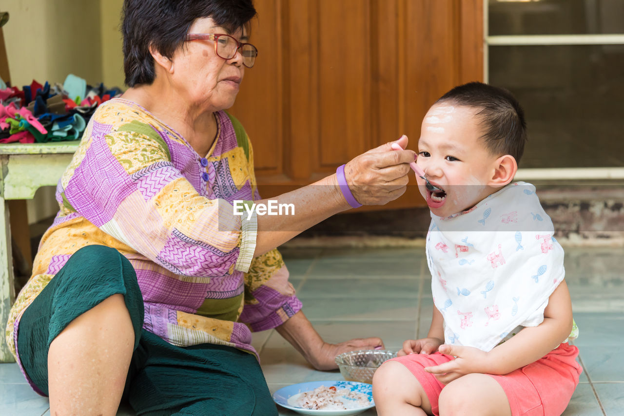 Grandmother feeding cute boy at home