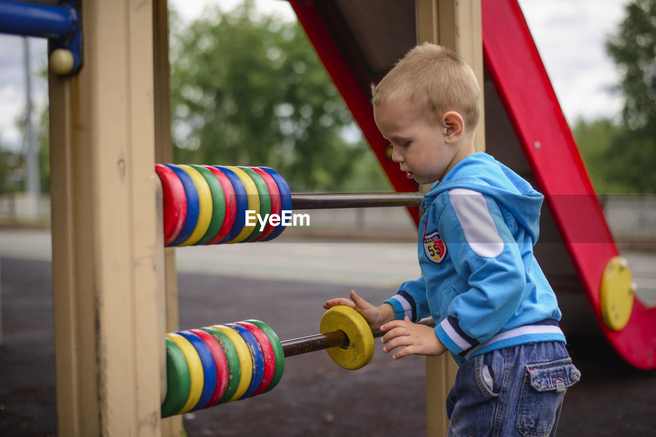 Side view of boy playing on slide at playground