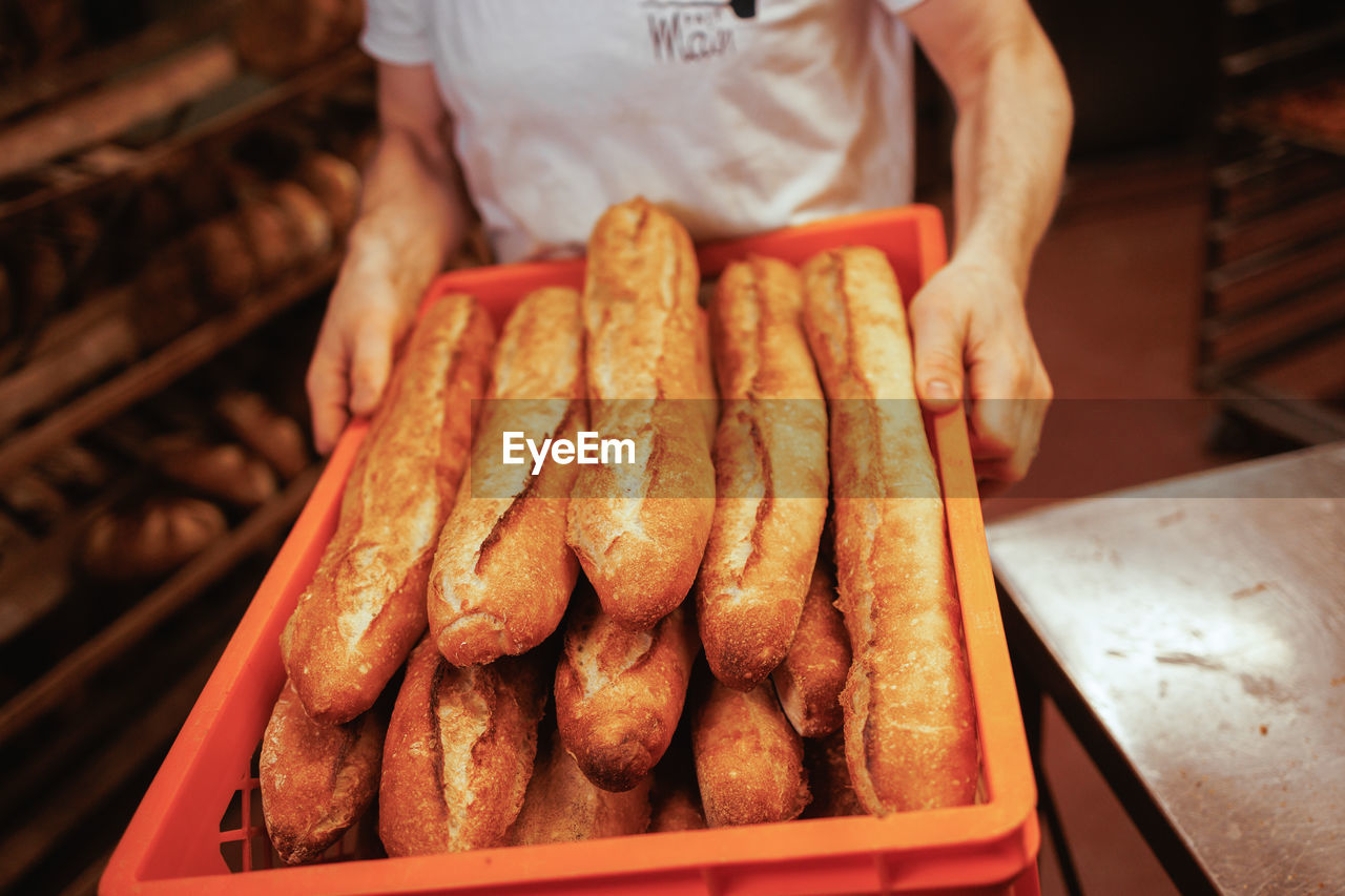 Midsection of man storing baguette bread