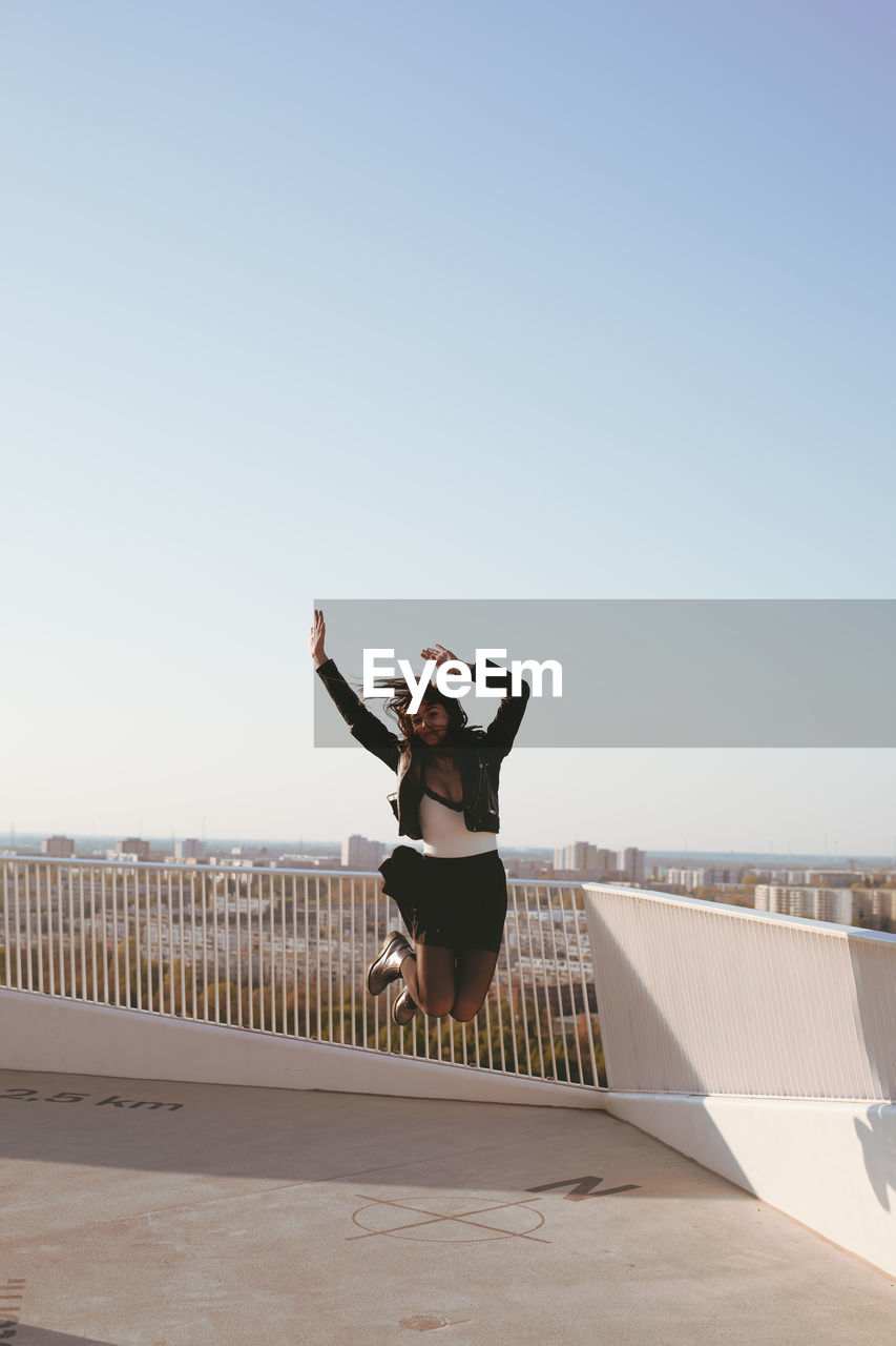 Woman jumping against clear sky