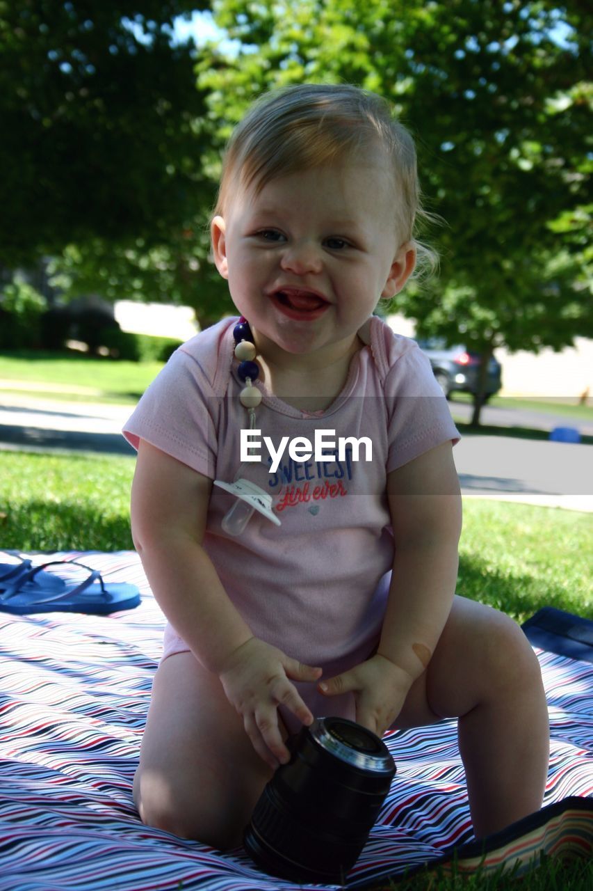 Cute baby girl sitting on picnic blanket at park