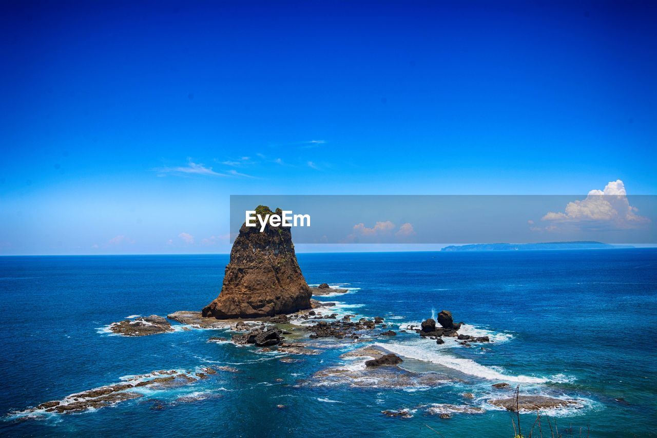 Rock formation in sea against blue sky