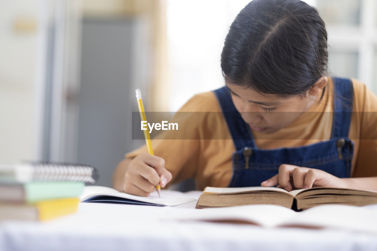 Asian girl reading and doing homework at her home