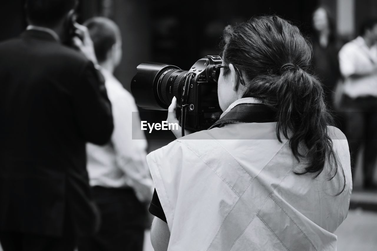 REAR VIEW OF YOUNG WOMAN PHOTOGRAPHING