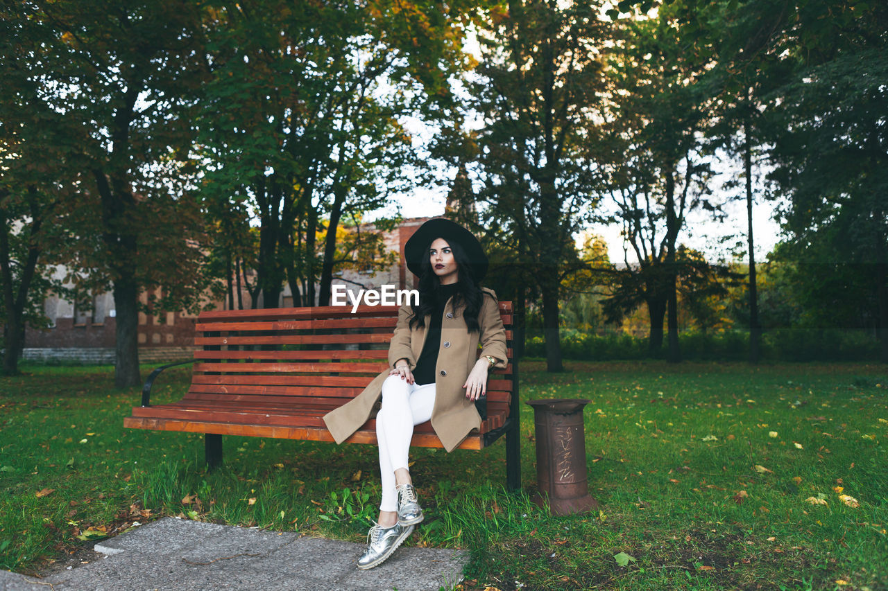 Portrait of woman sitting on bench in park