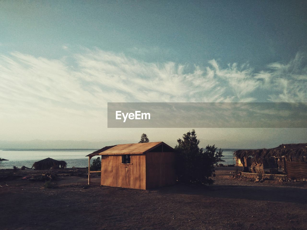 Hut at beach against cloudy sky