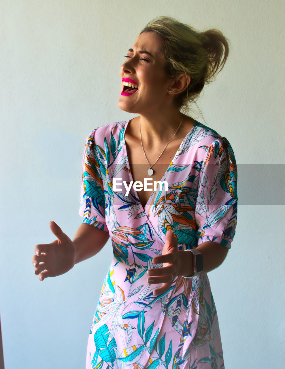 BEAUTIFUL YOUNG WOMAN STANDING AGAINST WALL AT HOME