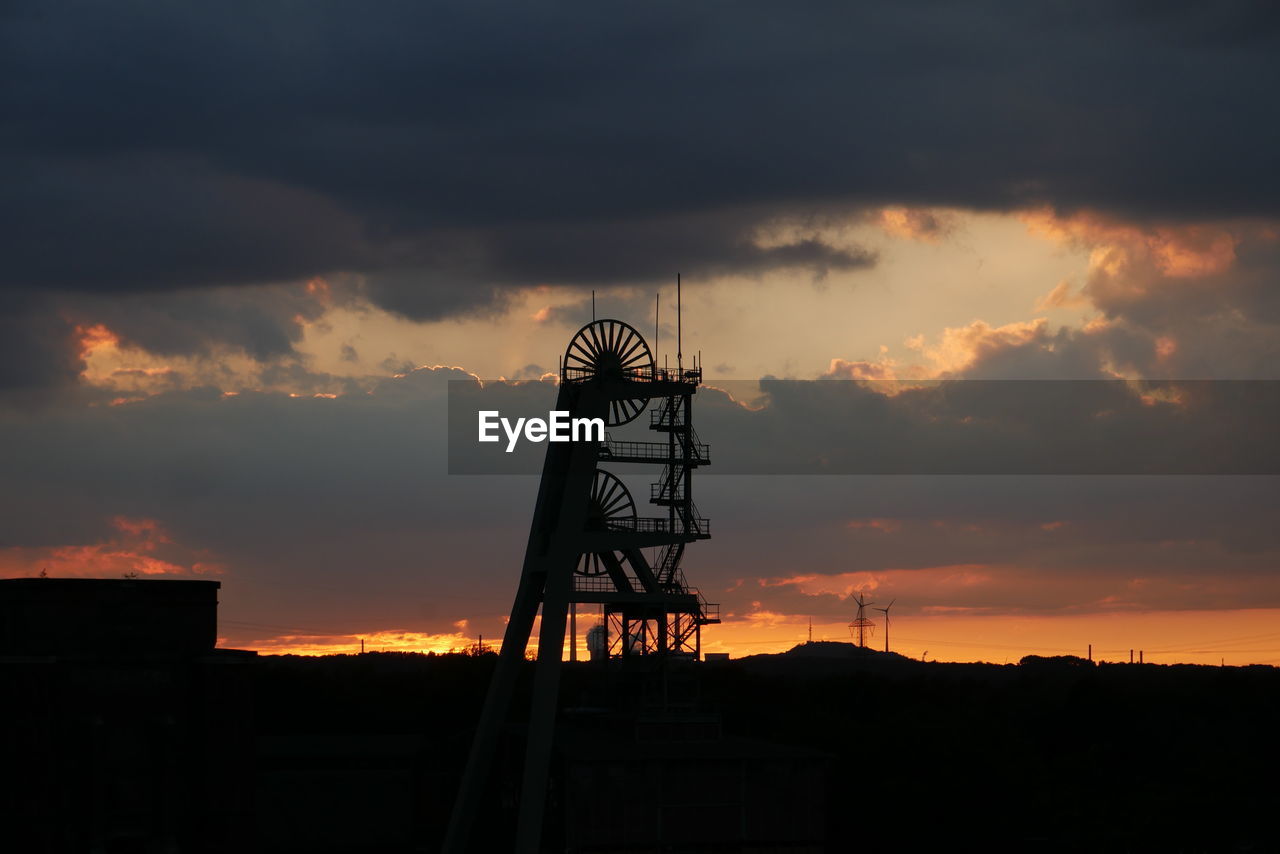 Low angle view of silhouette winding tower against sky during sunset