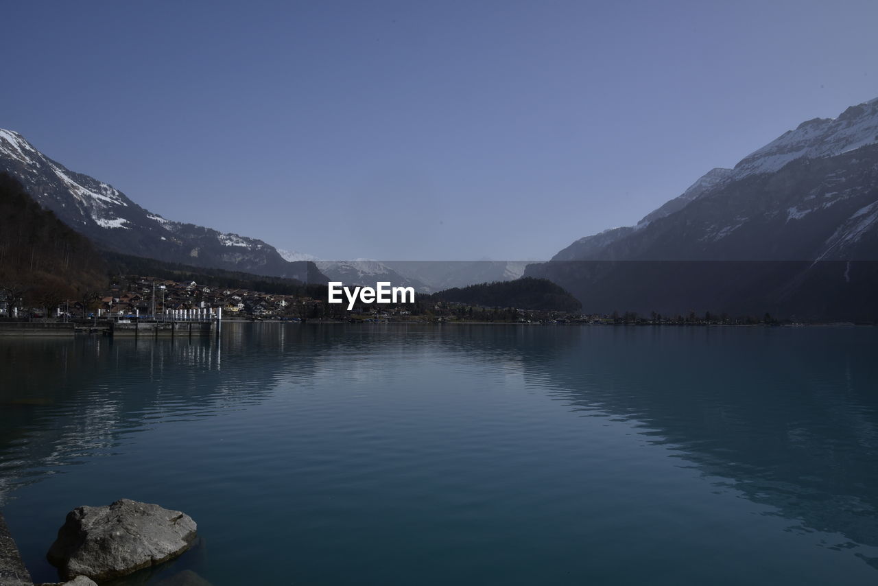 Scenic view of lake and mountains against clear blue sky