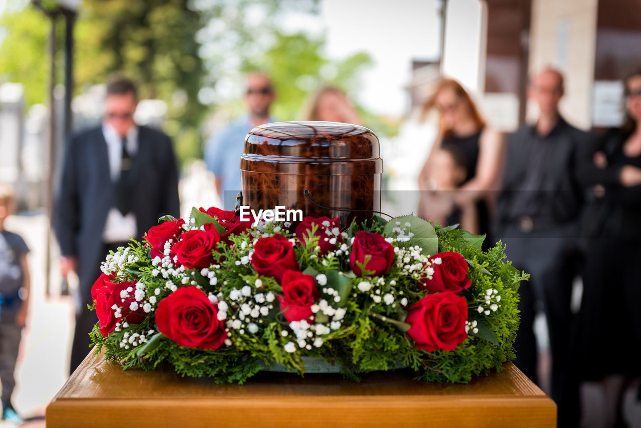 Funerary urn with ashes of dead and flowers at funeral.