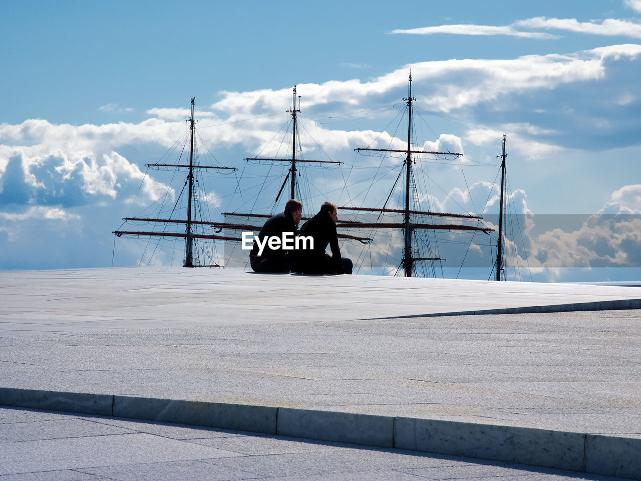 Friends sitting at pier against mast