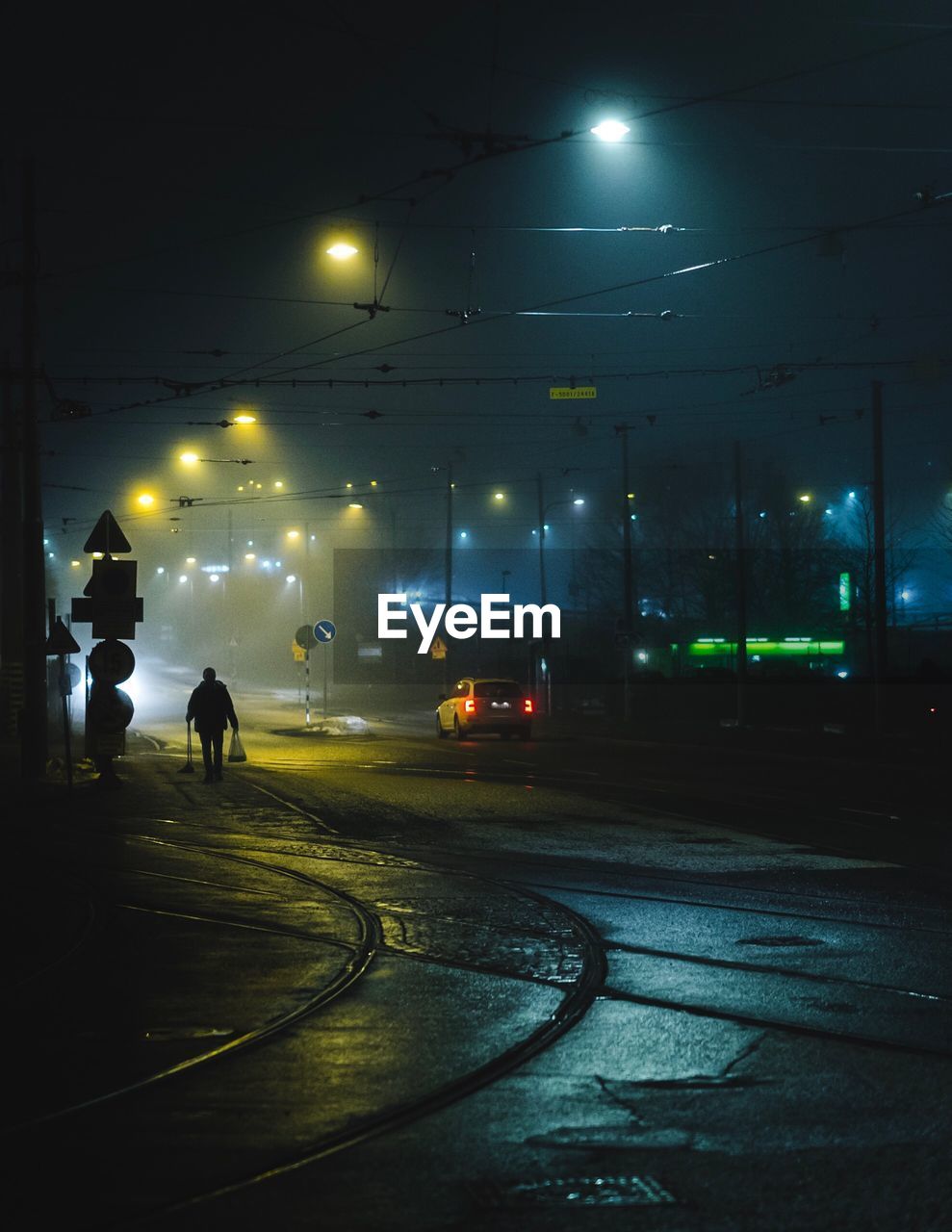 Man walking on illuminated street at night