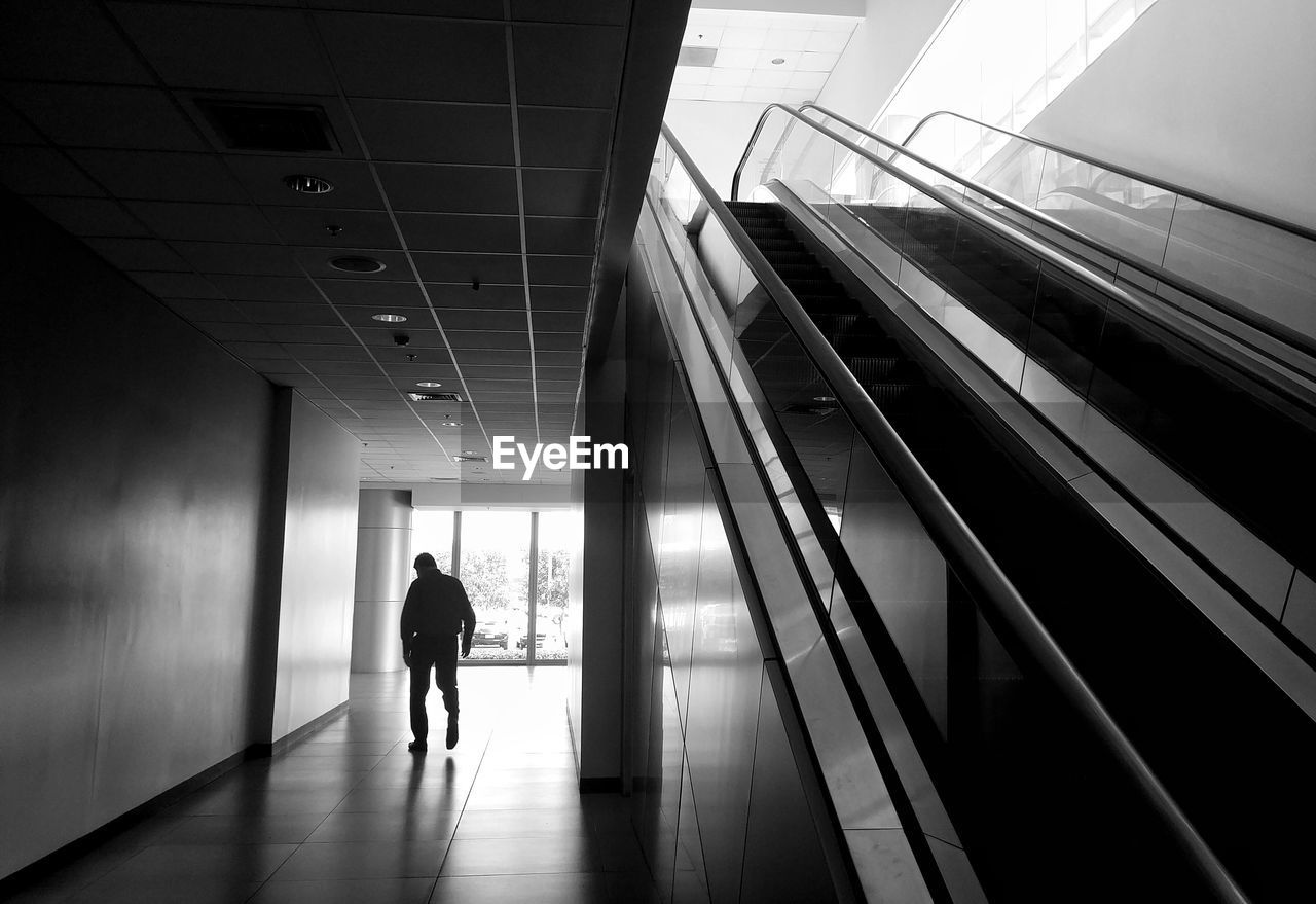Full length rear view of silhouette man walking in corridor of building