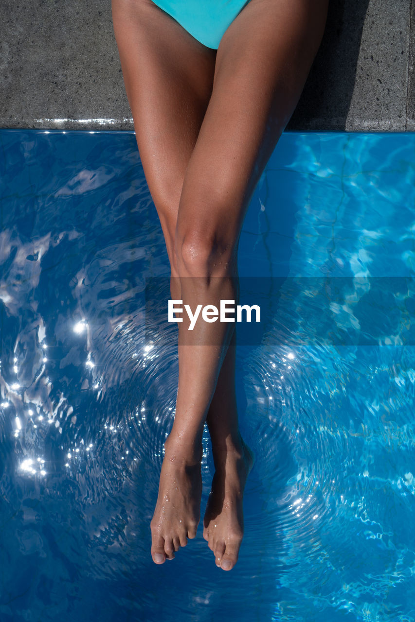 LOW SECTION OF WOMAN SWIMMING IN POOL
