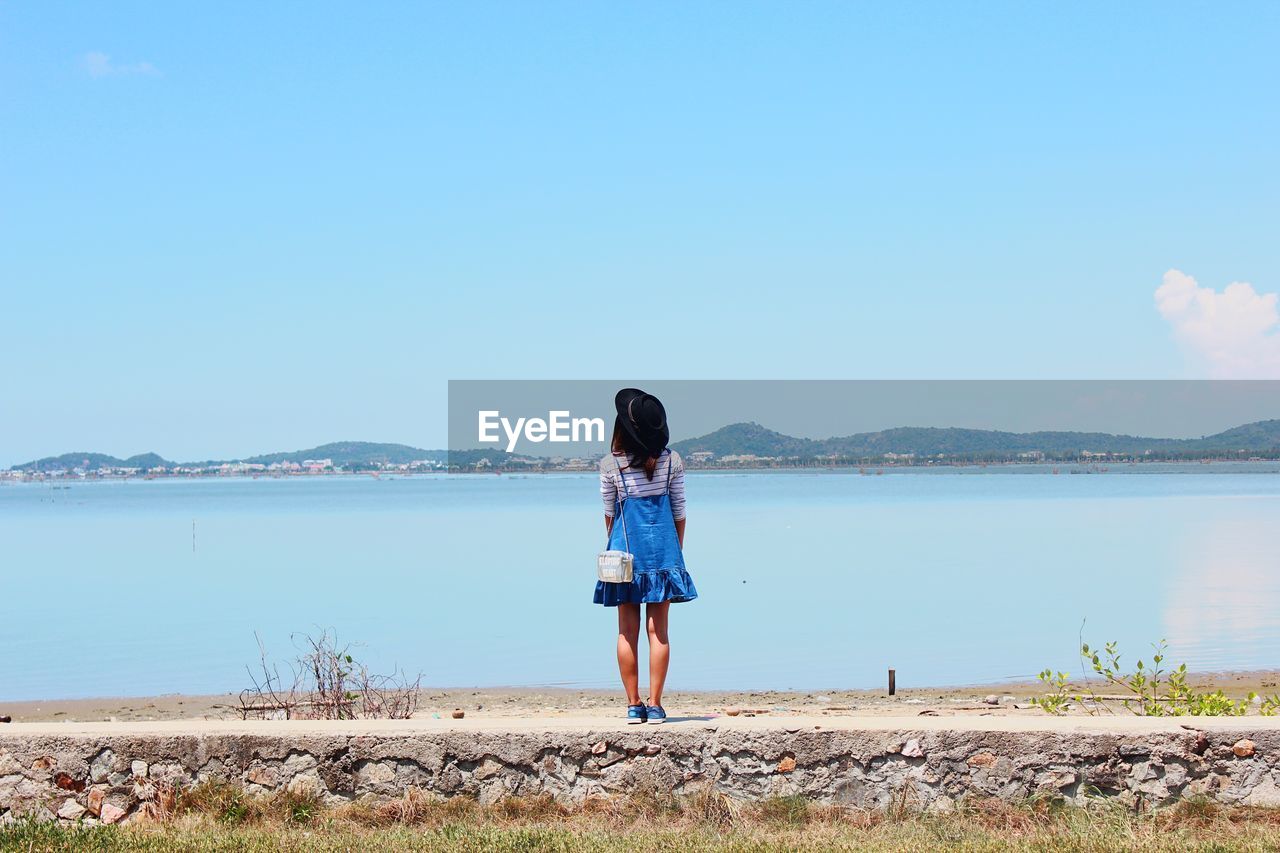 Rear view of woman standing by sea