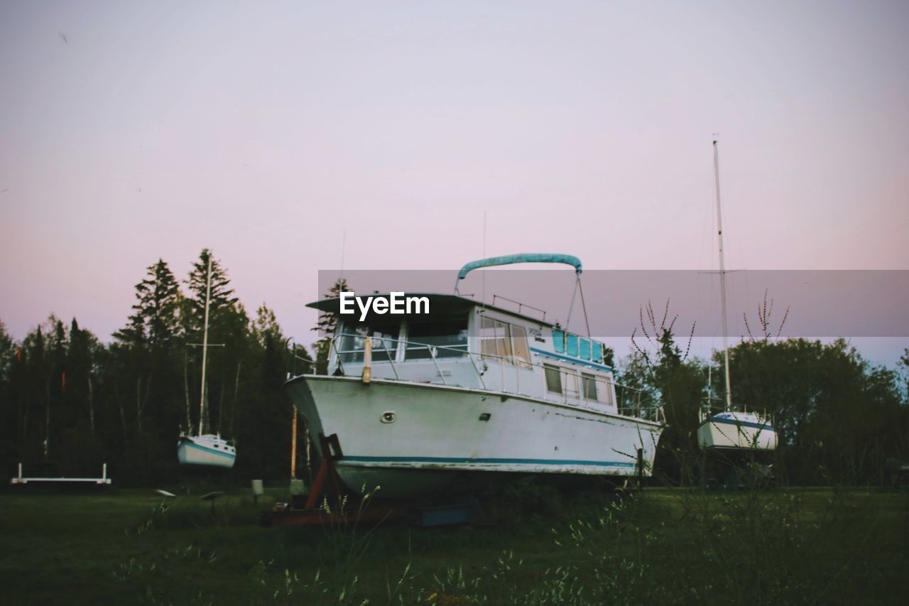 BOATS MOORED ON GRASS AGAINST CLEAR SKY