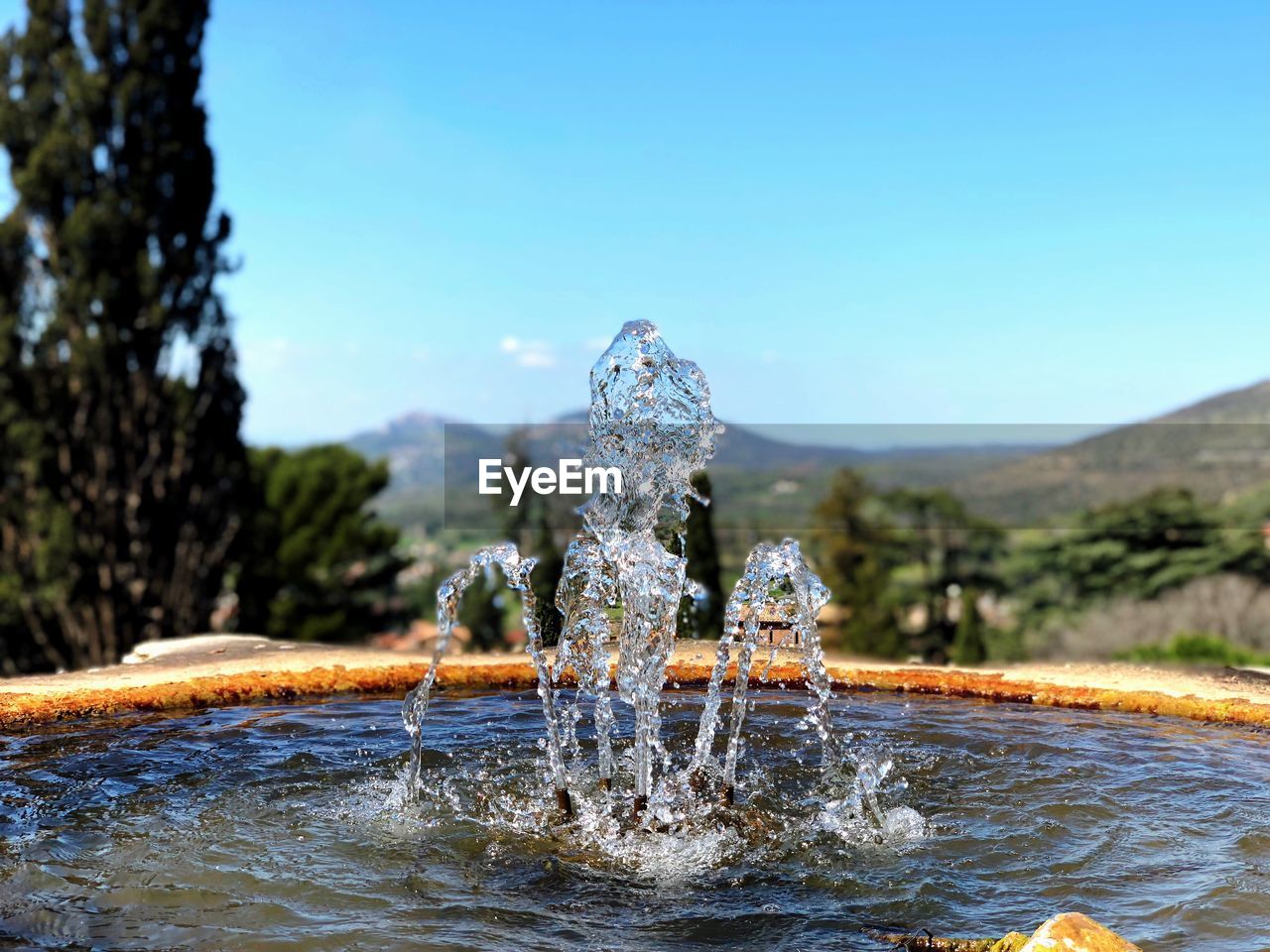 Water splashing in fountain against clear blue sky