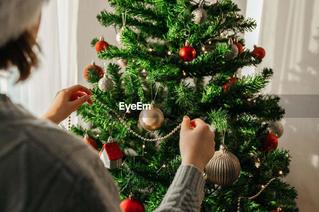 The girl decorates the christmas tree for the holiday. preparing for christmas and new year. 