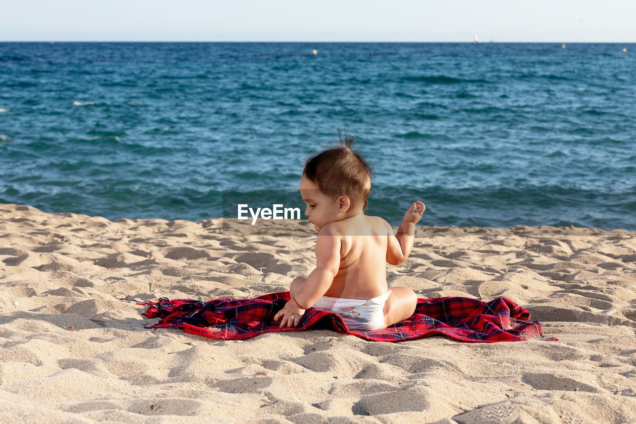 rear view of woman sitting on beach