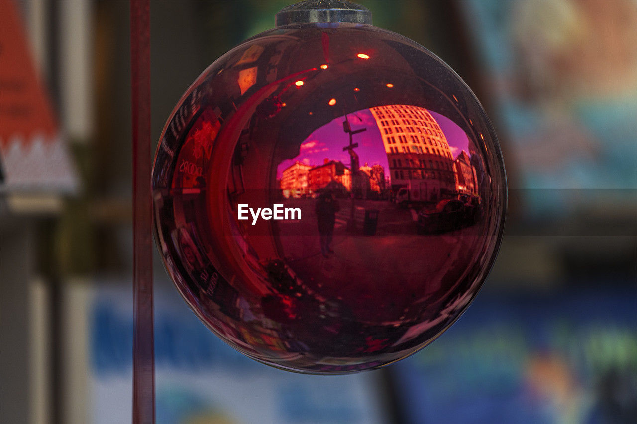 red, focus on foreground, reflection, close-up, glass, sphere, light, no people, outdoors, hanging, lighting, transparent, city