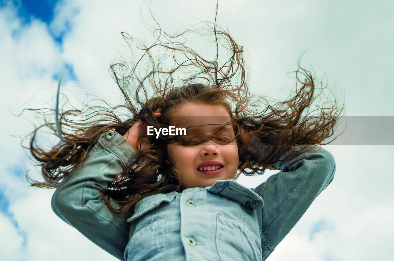 Low angle view of girl with long hair against sky