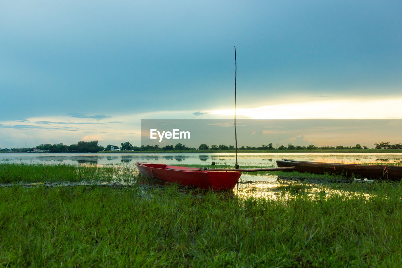 BOAT MOORED ON SHORE AGAINST SKY DURING SUNSET