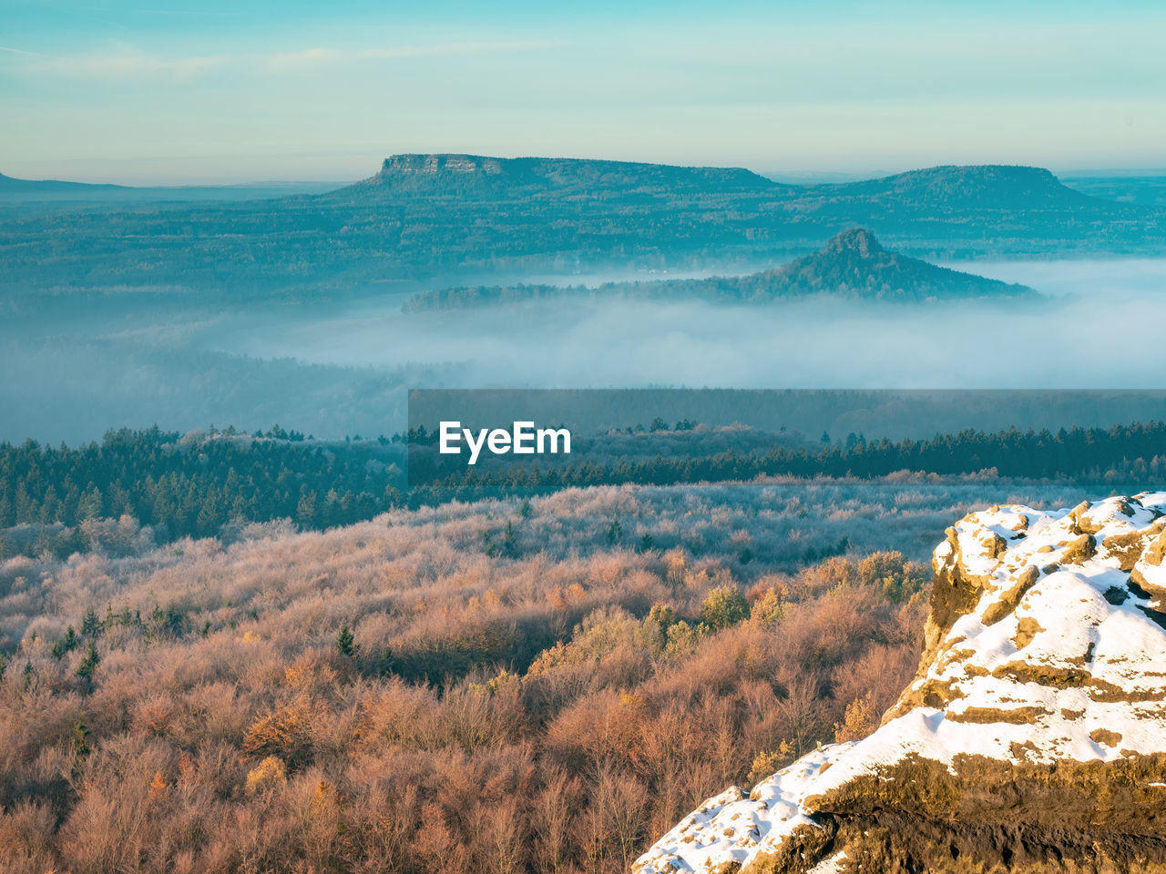 Snowy rocks above valley in saxony switzerland national park. elbe river valley in chill morning