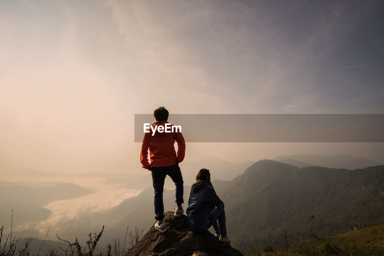 People looking at mountains against sky