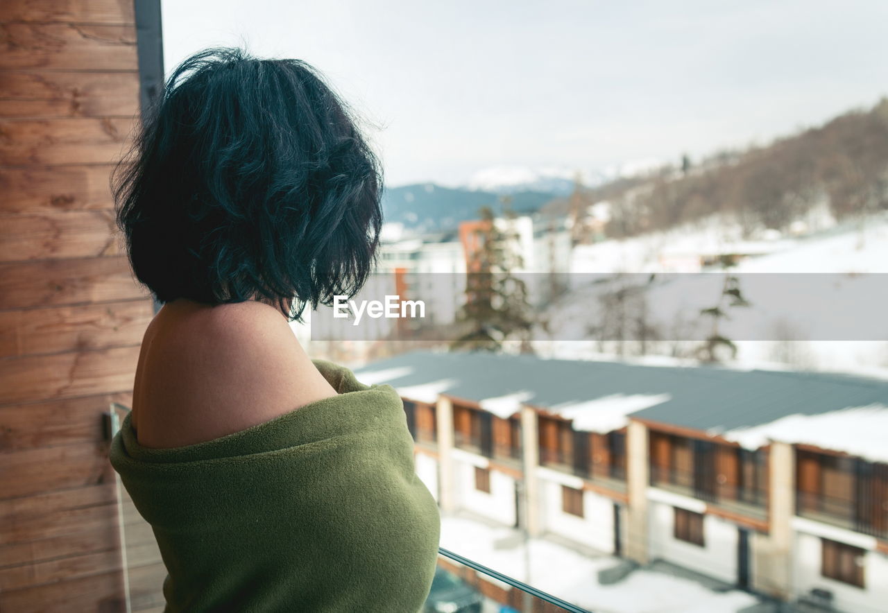 Side view of topless woman with blanket standing in balcony