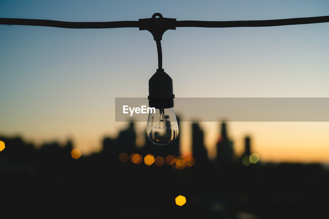 Close-up of light bulb against sky during sunset