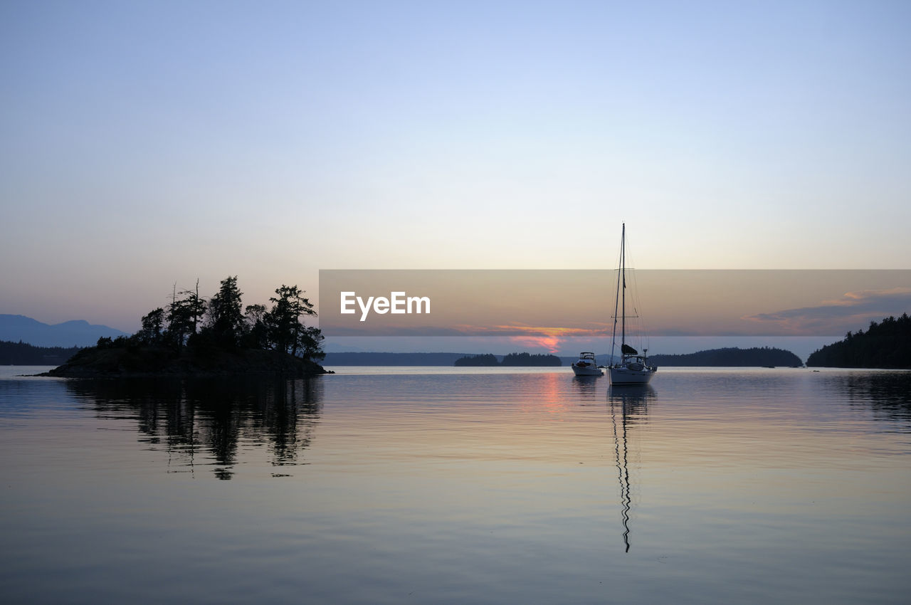 SILHOUETTE OF SAILBOATS IN LAKE AGAINST SKY DURING SUNSET