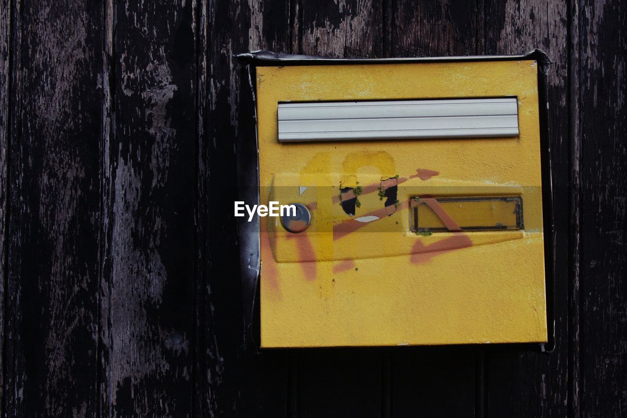 Close-up of yellow mailbox on wall