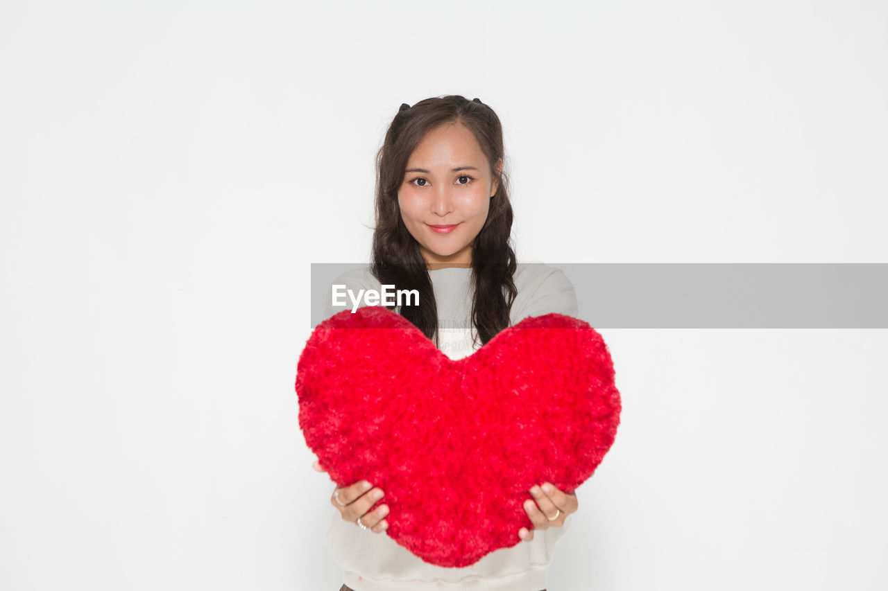 heart shape, emotion, positive emotion, valentine's day, pink, red, love, one person, portrait, white background, indoors, studio shot, heart, women, clothing, smiling, happiness, looking at camera, adult, copy space, young adult, waist up, long hair, front view, romance, person, brown hair, holding, cheerful, female, hairstyle, cut out, child, creativity