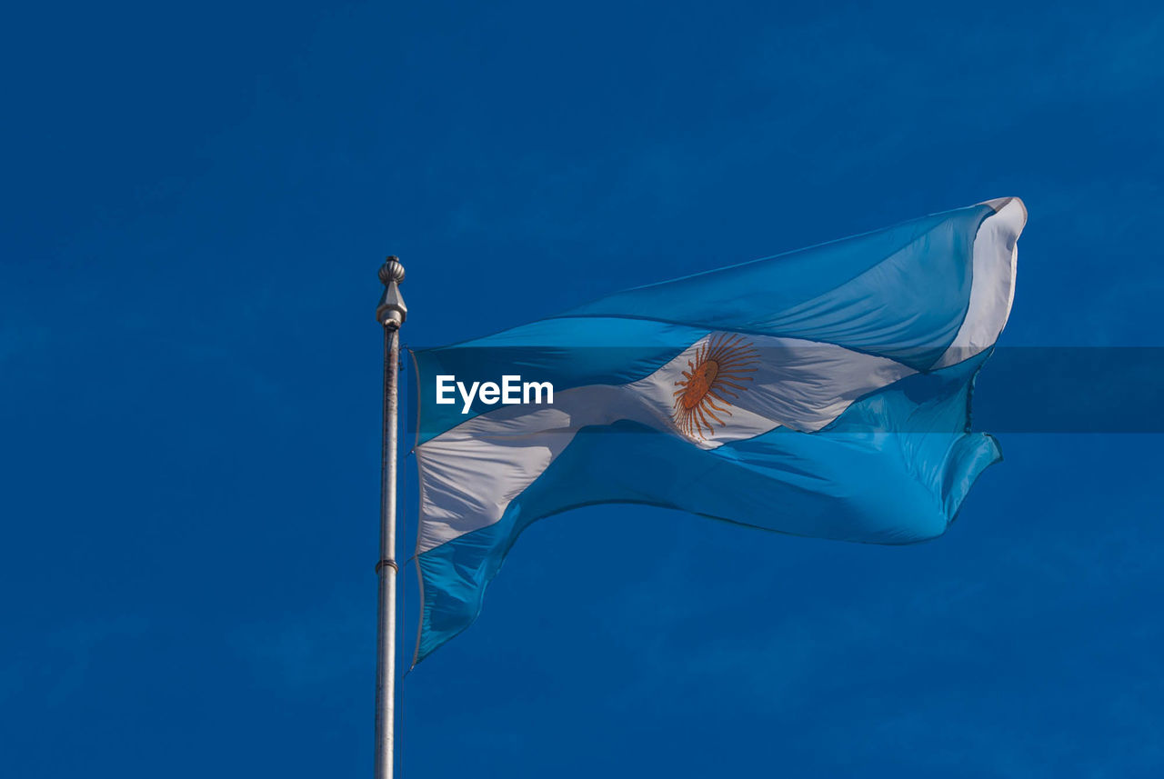 Low angle view of argentinian flag against blue sky