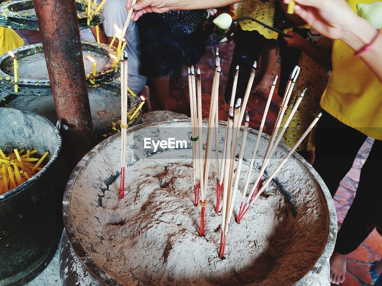 Midsection of people by incense sticks in temple