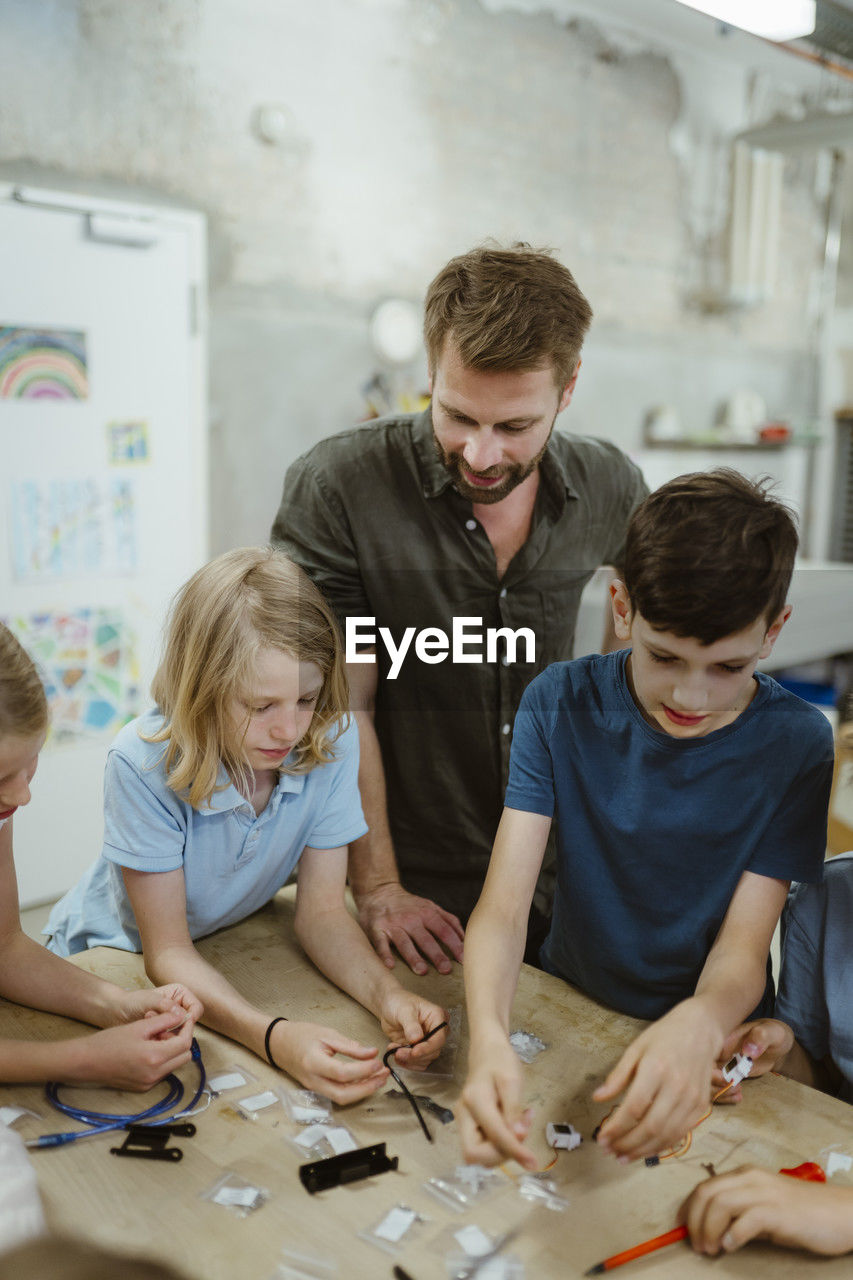 Male teacher assisting students during technology class