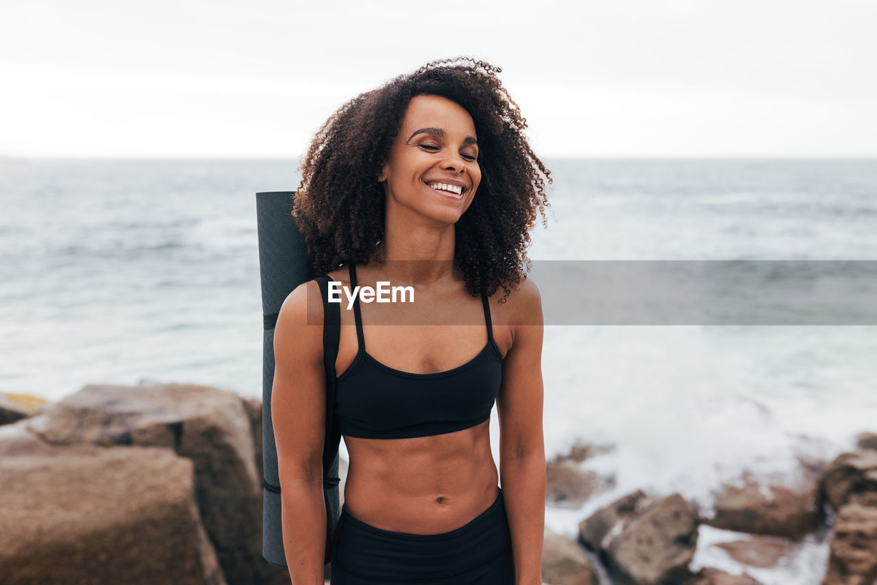 portrait of beautiful young woman standing at beach