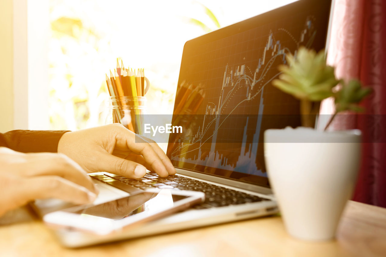 MIDSECTION OF MAN USING LAPTOP