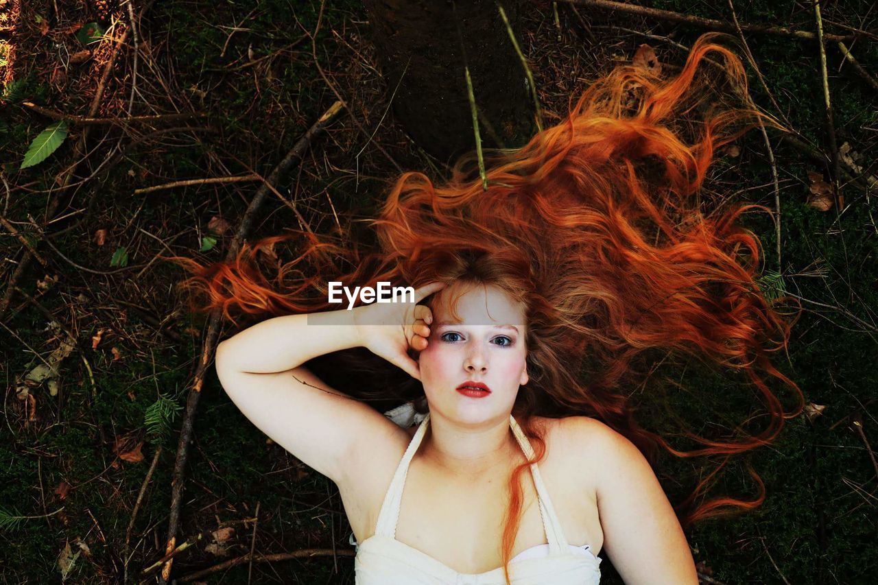 Portrait of young woman lying down on field