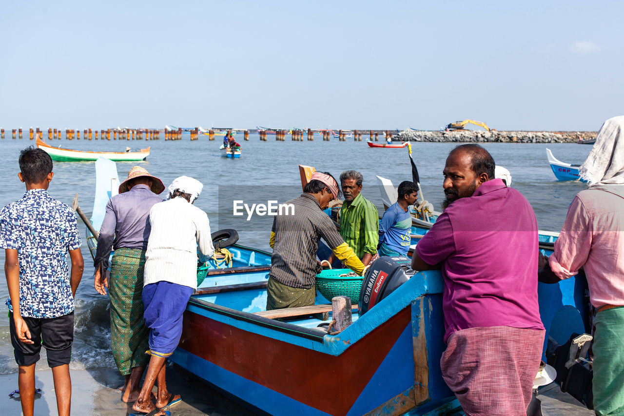 REAR VIEW OF PEOPLE ENJOYING IN SEA