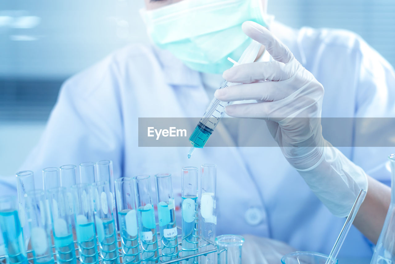 Midsection of scientist examining chemical in laboratory