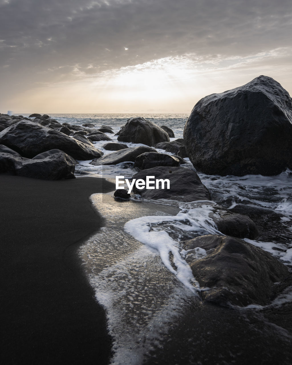 Rocks in sea against sky during sunset