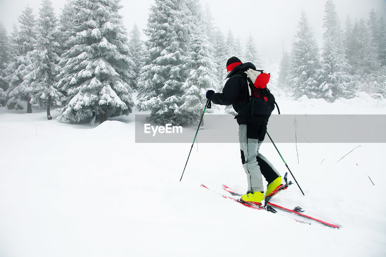 Side view of man skiing on snow covered field