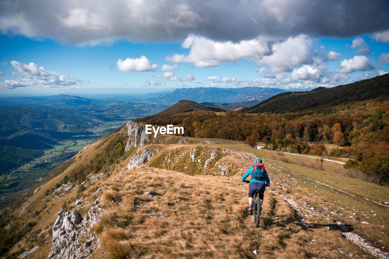 Woman mountain biking on footpath near ridge on mount nanos above vipava, slovenia.