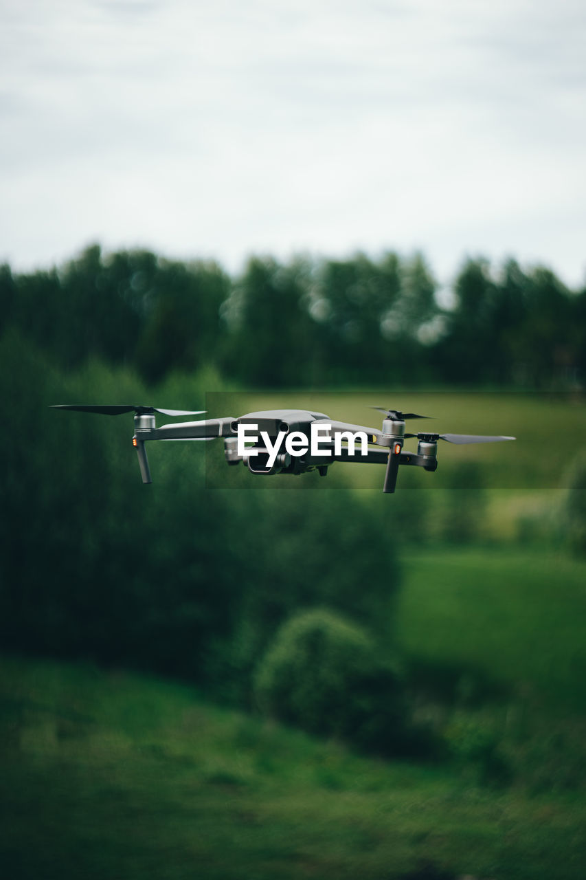 Drone flying over land against sky