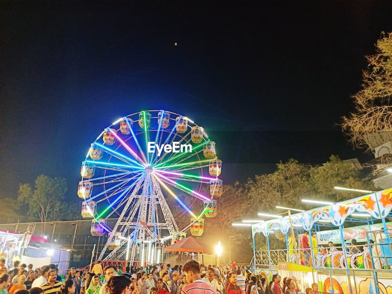 VIEW OF ILLUMINATED FERRIS WHEEL AT NIGHT